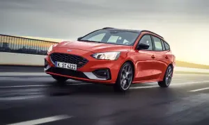 Czerwony Ford Focus sedan ST pędzi po drodze, z rozmytym tłem sugerującym dużą prędkość.