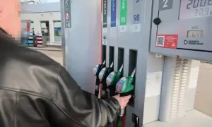 Mężczyzna w czarnej kurtce sięga po dystrybutor z napisem "verva diesel" na stacji paliw.