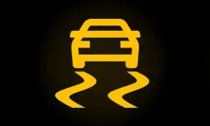 Żółty symbol ESP w samochodzie, pokazujący auto na śliskiej drodze. Uważaj na zakrętach!
