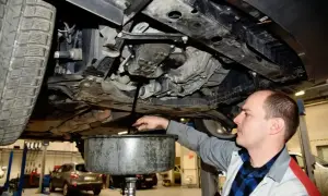 Mechanik spuszcza olej z silnika samochodu. Pamiętaj o regularnej wymianie oleju, by auto służyło Ci długo.