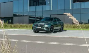 Zielony Mercedes-Benz GLE 450d coupe zaparkowany przed nowoczesnym budynkiem z lustrzanymi oknami.