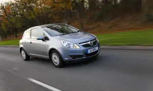 Srebrny Opel Corsa D 1.2 benzyna w ruchu, z rozmytym tłem jesiennego lasu.