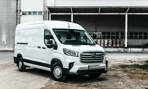 Biały Maxus Deliver 9 stoi przed magazynem. Ten wszechstronny van jest gotowy do pracy, przewożąc towary z miejsca na miejsce.