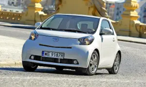 Biały, kompaktowy samochód Toyota iQ z polskimi tablicami WE 9187R jedzie po moście. Ten model, choć nie jest Daihatsu, oferuje podobną zwinność w mieście.