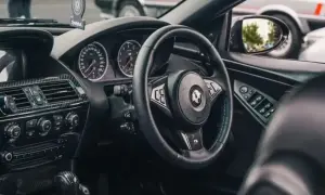Wnętrze BMW E64 z czarną kierownicą, deską rozdzielczą i elementami z włókna węglowego.