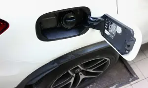 Otwarty wlew paliwa w białym Mitsubishi ASX 1.6 benzyna. Widoczny korek i tabliczka informacyjna.