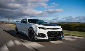 Białe Camaro ZL1 z czarną maską i spoilerem pędzi po torze wyścigowym, zostawiając za sobą rozmyte tło.