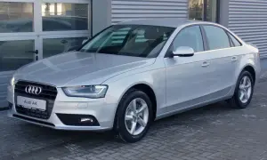 Srebrne Audi A4 B8, znane z typowych usterek, stoi przed budynkiem.