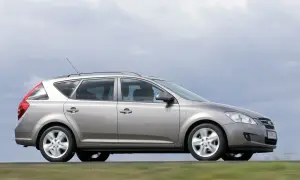 Srebrny Kia Ceed 1.6 benzyna w wersji kombi jedzie po drodze, za nim rozmyte zielone pola.