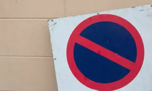 Znak zakazu zatrzymywania się, b35 znak, na tle beżowej ściany.