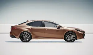 Elegancka, brązowa Toyota Camry 2.5 Hybrid w profilu, prezentująca nowoczesny design i dynamiczną sylwetkę.