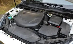 Silnik D2 w Volvo V40, gotowy do pracy. Widać osłonę silnika z logo Volvo, skrzynkę bezpieczników i elementy układu dolotowego.