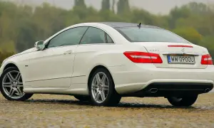 Biały w212 coupe z polskimi tablicami rejestracyjnymi stoi na mokrej nawierzchni.