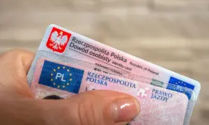 Dłoń trzyma polski dowód osobisty i prawo jazdy. Dokumenty te są niezbędne do poruszania się po drogach, a prawo jazdy bezterminowe daje swobodę na lata.