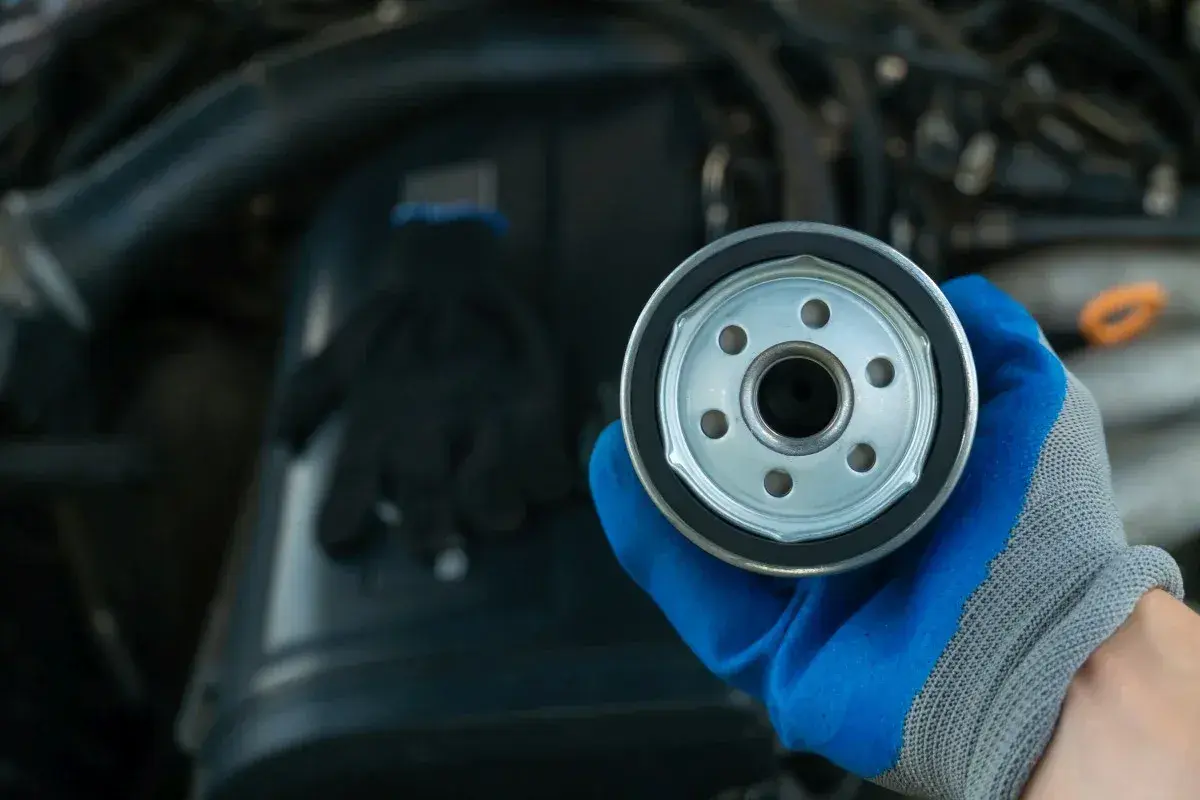 Nowy filtr oleju do silnika 1.6 TDI. Ręka w niebieskiej rękawicy trzyma filtr.