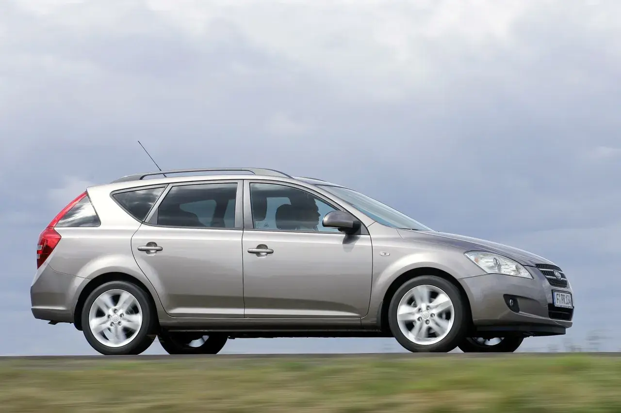Srebrny Kia Ceed 1.6 benzyna w wersji kombi jedzie po drodze, za nim rozmyte zielone pola.