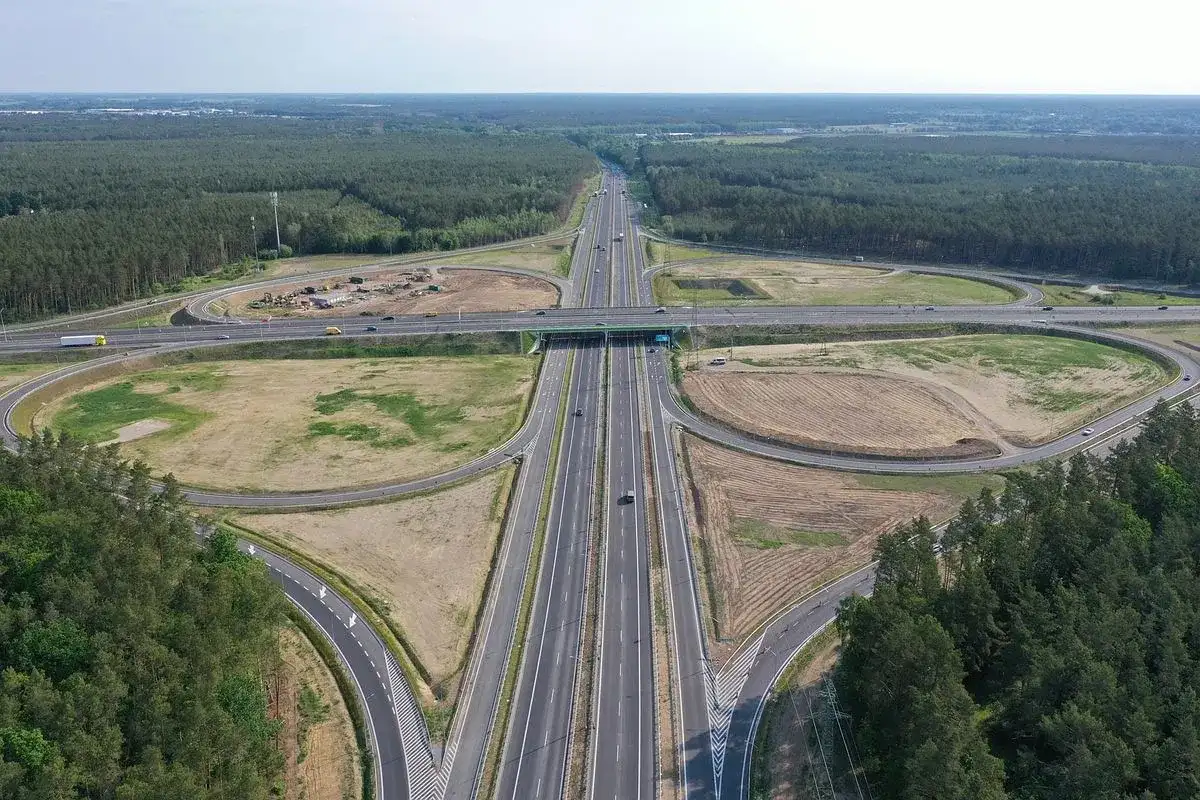 Rozległy węzeł drogowy autostrady A6 otoczony lasami. Widać wielopoziomowe skrzyżowania, drogi dojazdowe i pasy ruchu.