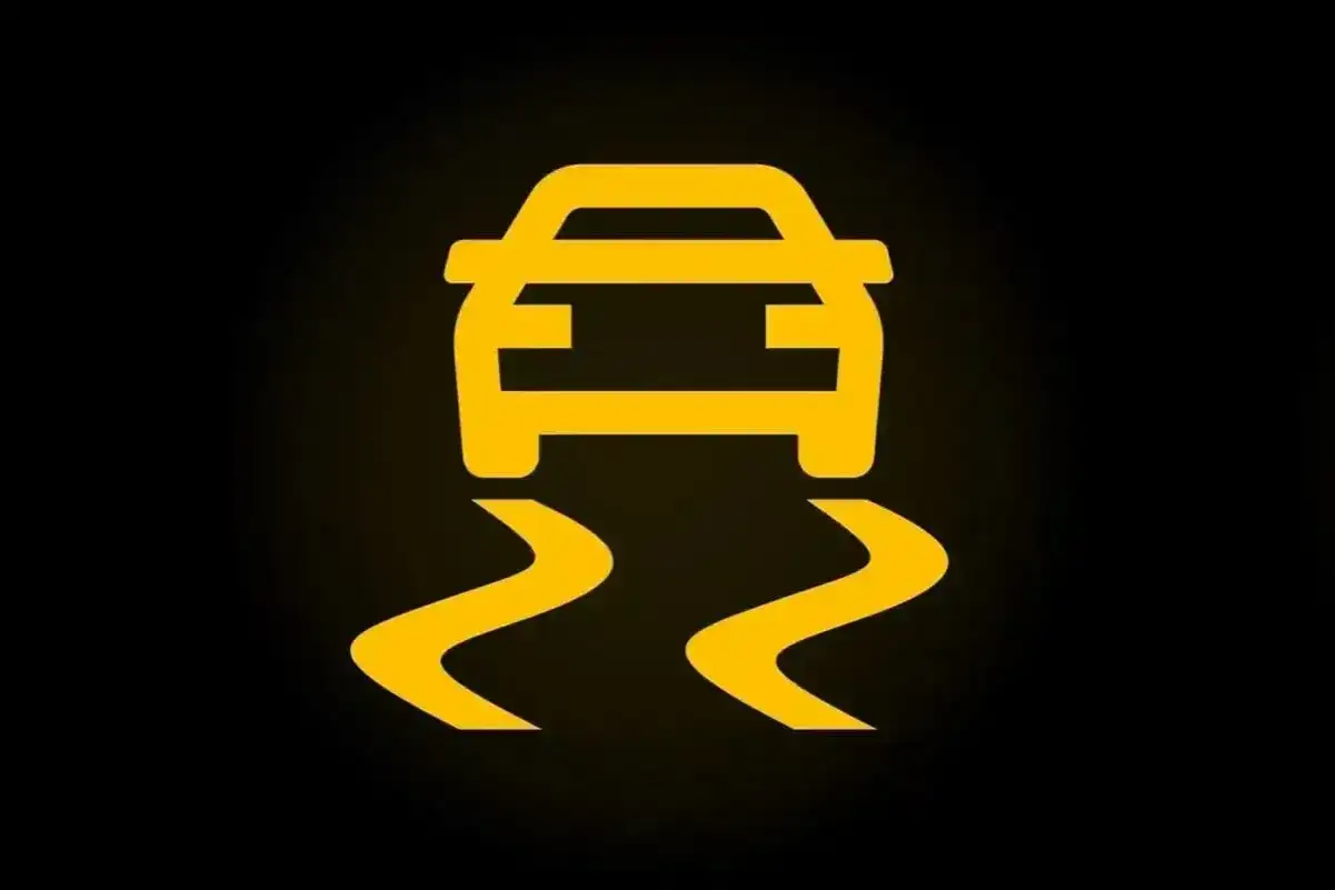 Żółty symbol ESP w samochodzie, pokazujący auto na śliskiej drodze. Uważaj na zakrętach!