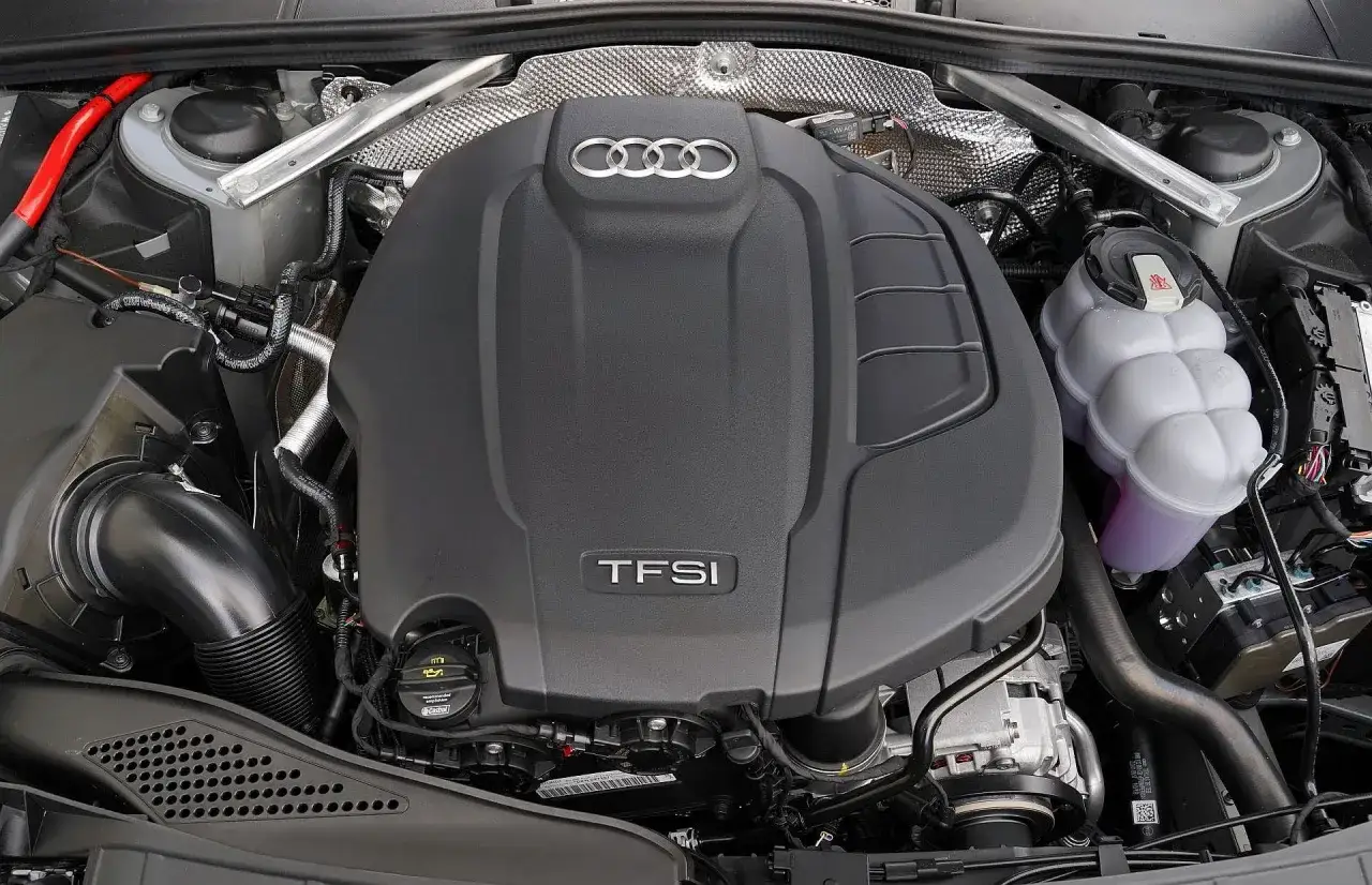 Silnik TFSI Audi z logo marki. Widoczny zbiornik płynu chłodniczego i elementy układu dolotowego.