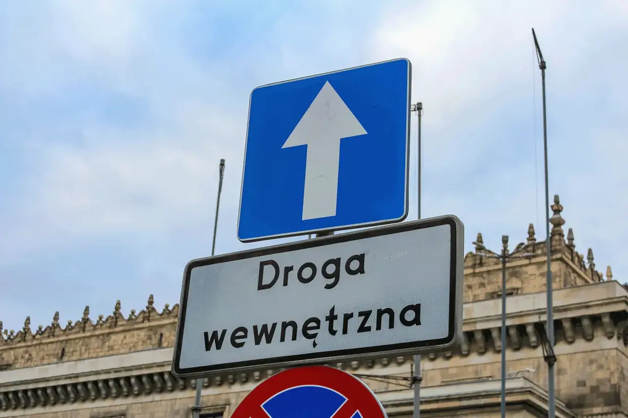 Niebieski znak z białym szpicem w górę i tabliczka
