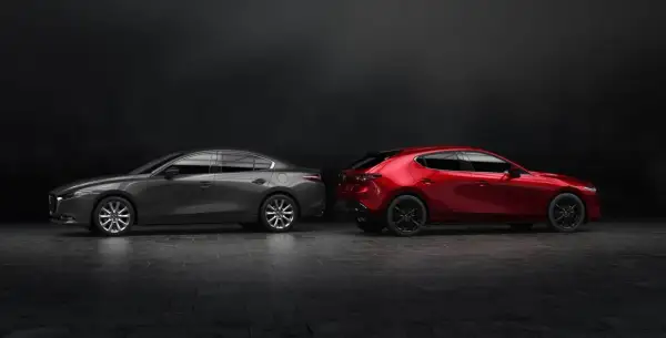 Szary sedan Mazda 3 i czerwony hatchback stoją obok siebie na ciemnym tle.