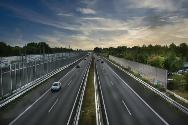 Szeroka autostrada bursztynowa z ruchem samochodowym pod pochmurnym niebem.