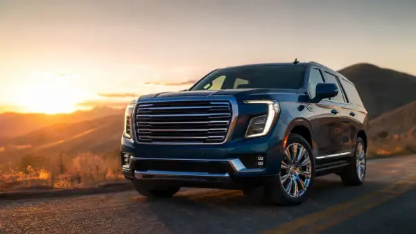 GMC Yukon XL w kolorze granatowym na tle zachodzącego słońca w górach.