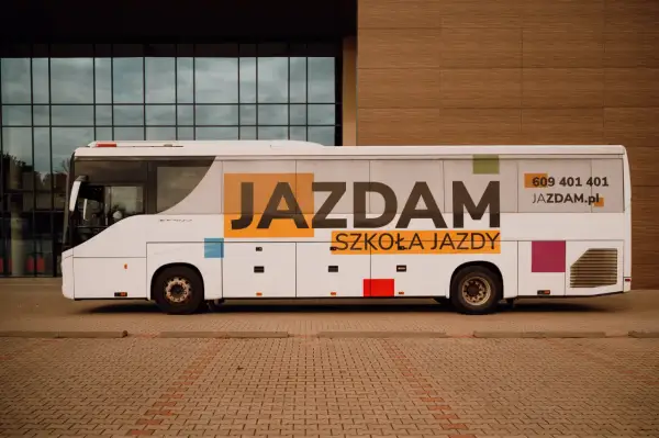 Biały autokar z napisem "JAZDAM SZKOŁA JAZDY" i numerem telefonu. Idealny do nauki jazdy kategorii D.