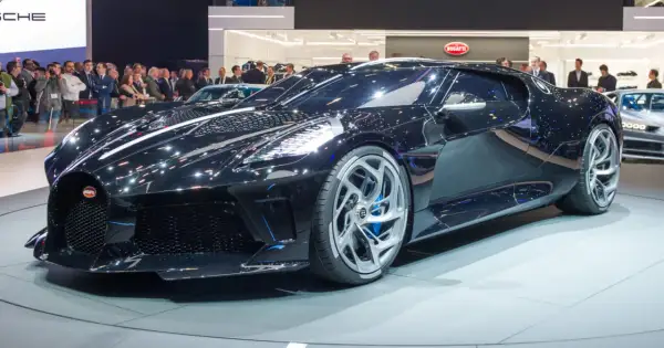 Lśniący, czarny Bugatti La Voiture Noire na wystawie, otoczony tłumem widzów.