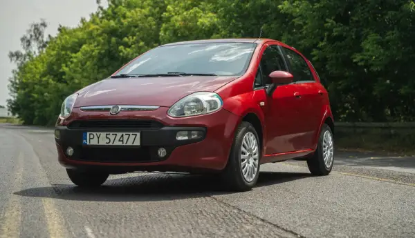 Czerwony Fiat Grande Punto na tle zieleni.
