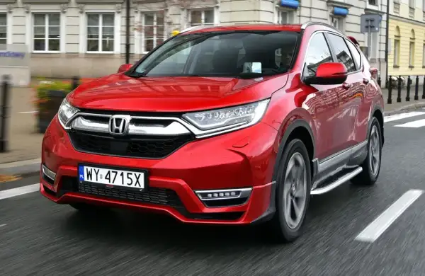 Czerwony Honda CRV 2024 jedzie ulicą.